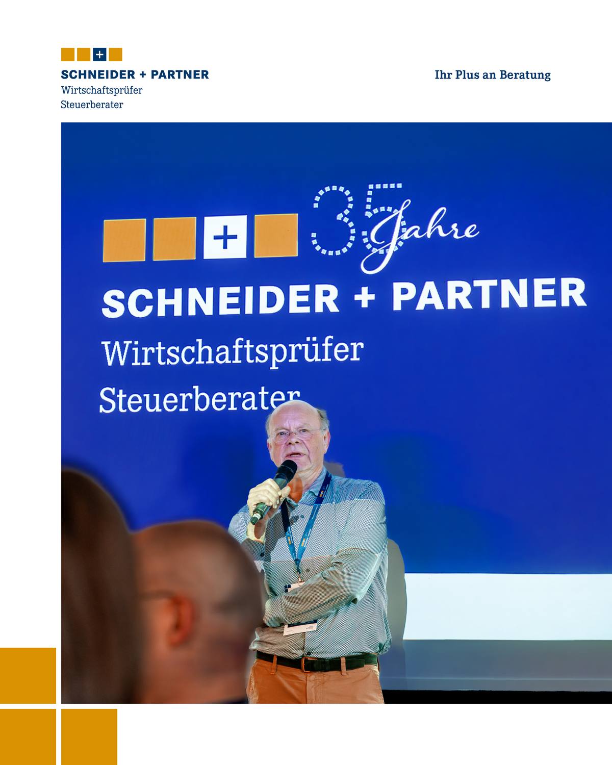 Ein Mann spricht in ein Mikrofon, hinter ihm ist auf einer Leinwand ein Firmenlogo zu sehen.