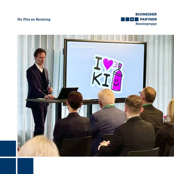 Ein Redner steht vorm Publikum, auf dem Monitor hinter ihm steht &quot;I love KI&quot;